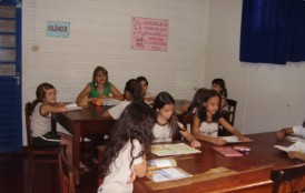 Alunas lendo em mesas da biblioteca